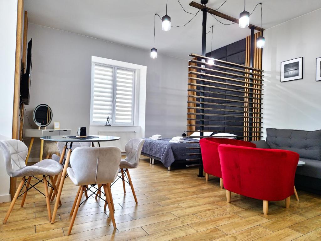 ein Wohnzimmer mit einem Bett und roten Stühlen in der Unterkunft Wieczorek Apartment in Kudowa-Zdrój
