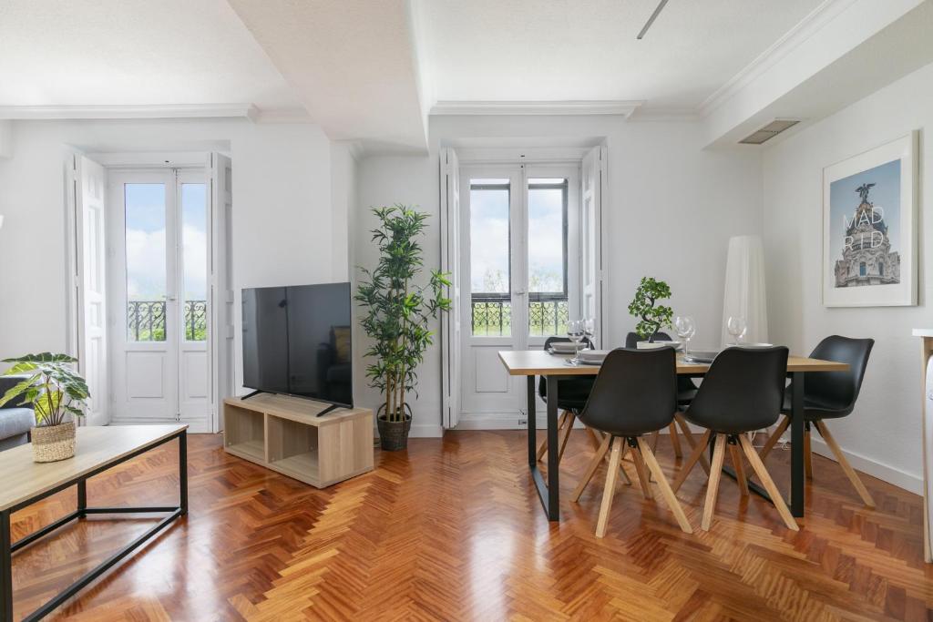 a living room with a table and chairs and a television at Piso luminoso con balcones frente Parque Retiro in Madrid