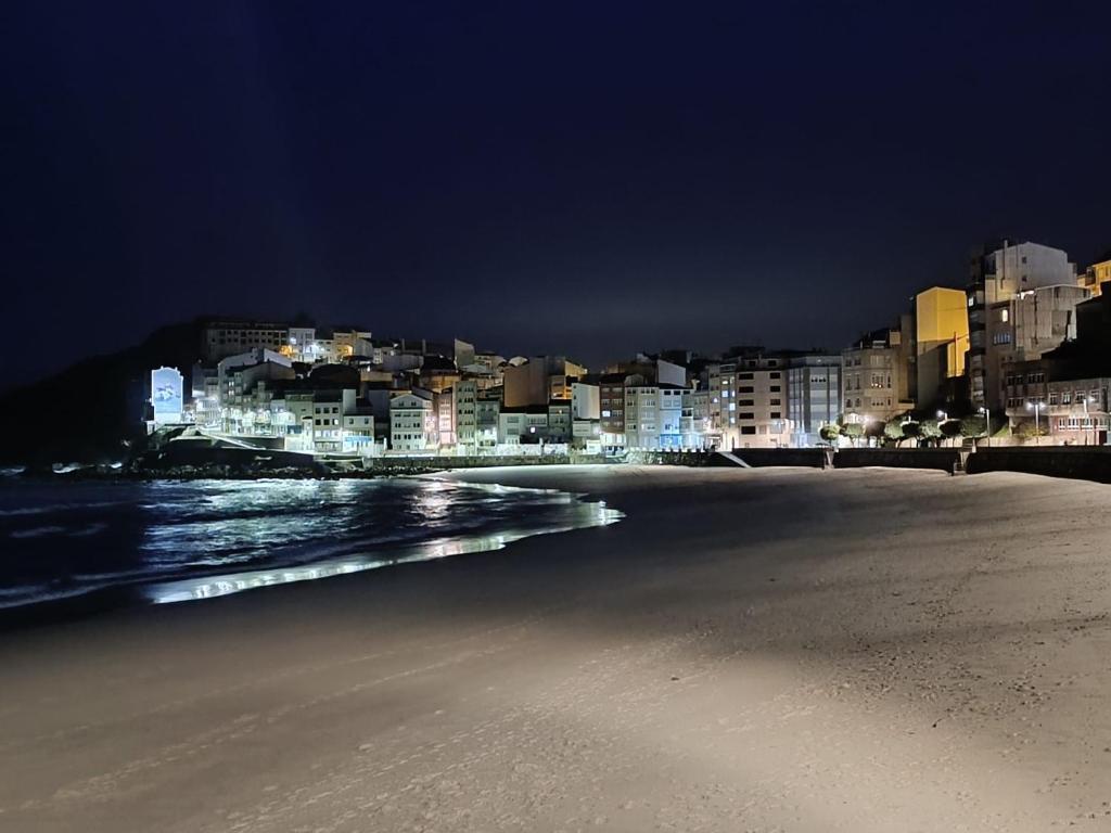 una spiaggia con una città sullo sfondo di notte di Apartamento con vistas al mar a Malpica de Bergantiños