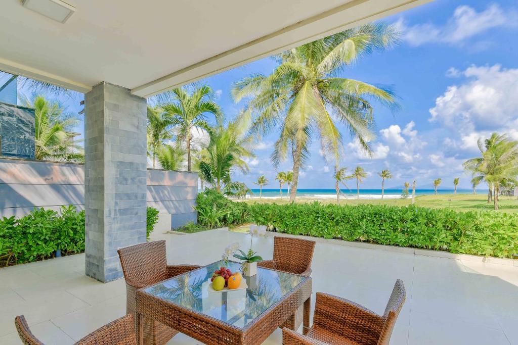 einen Tisch und Stühle auf einer Terrasse mit Meerblick in der Unterkunft Golden Beachside Resort Danang in Đà Nẵng