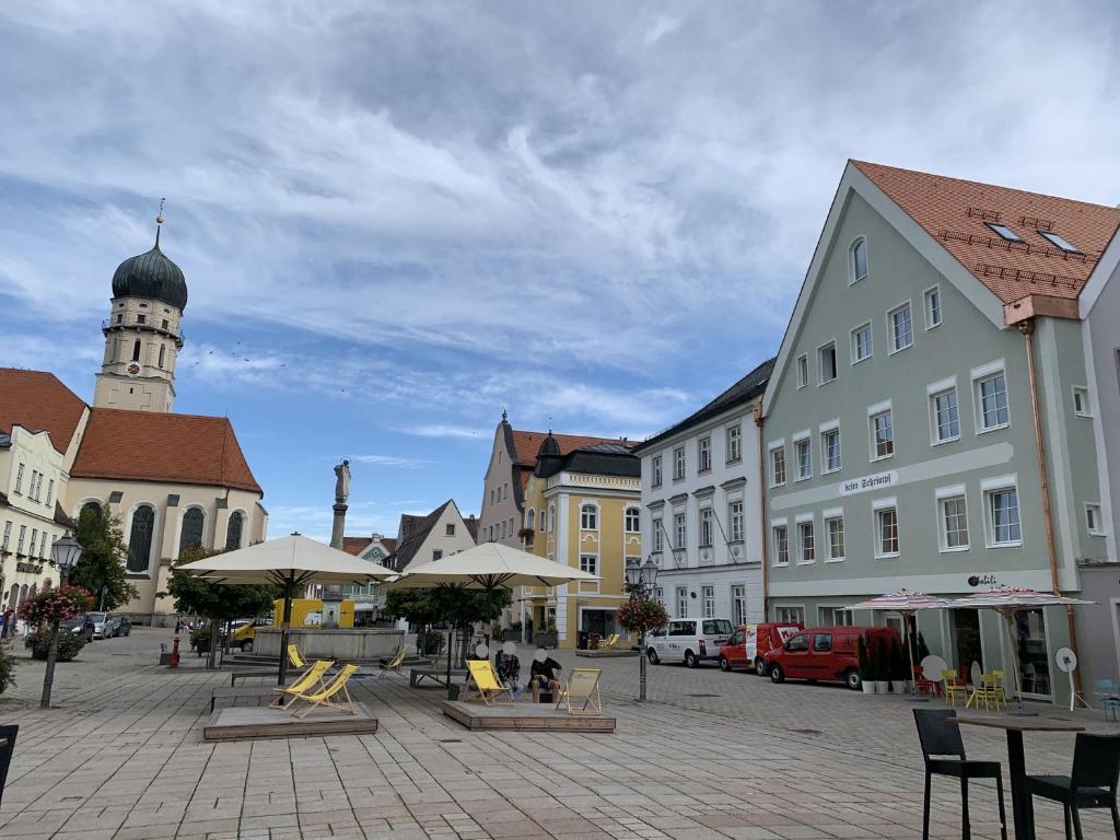 une place de ville avec des tables, des chaises et des bâtiments dans l'établissement Ferienwohnung "beim Schrimpf", à Schongau