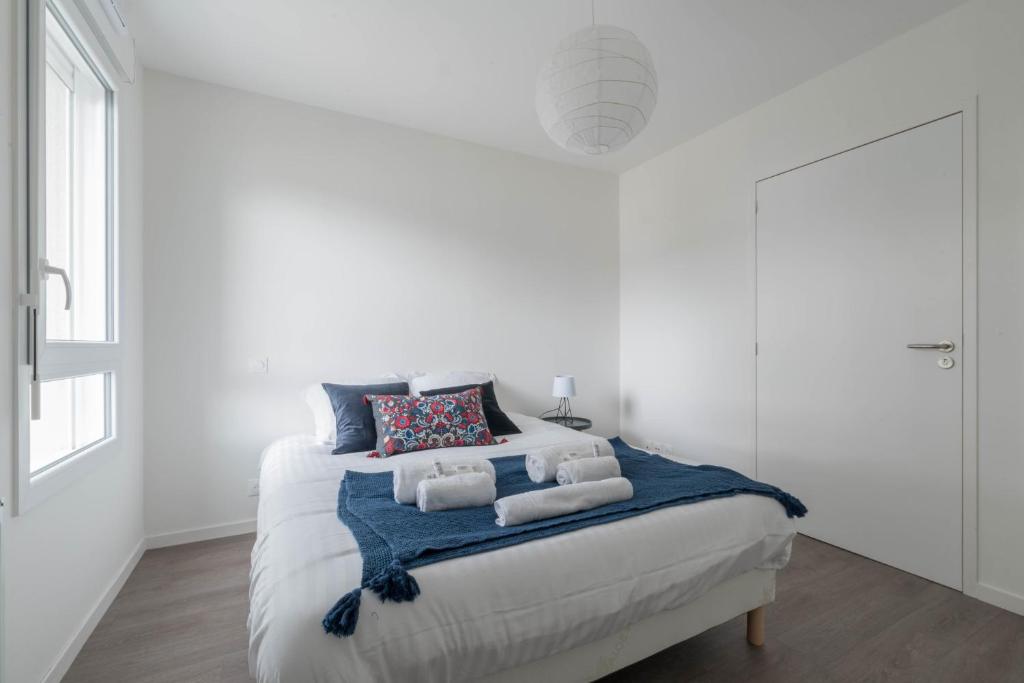 a white bedroom with a bed with a blue blanket at Elodie - T2 proche gare in Le Mans