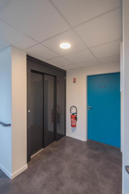 an empty room with a blue door and a fire extinguisher at Elodie - T2 proche gare in Le Mans