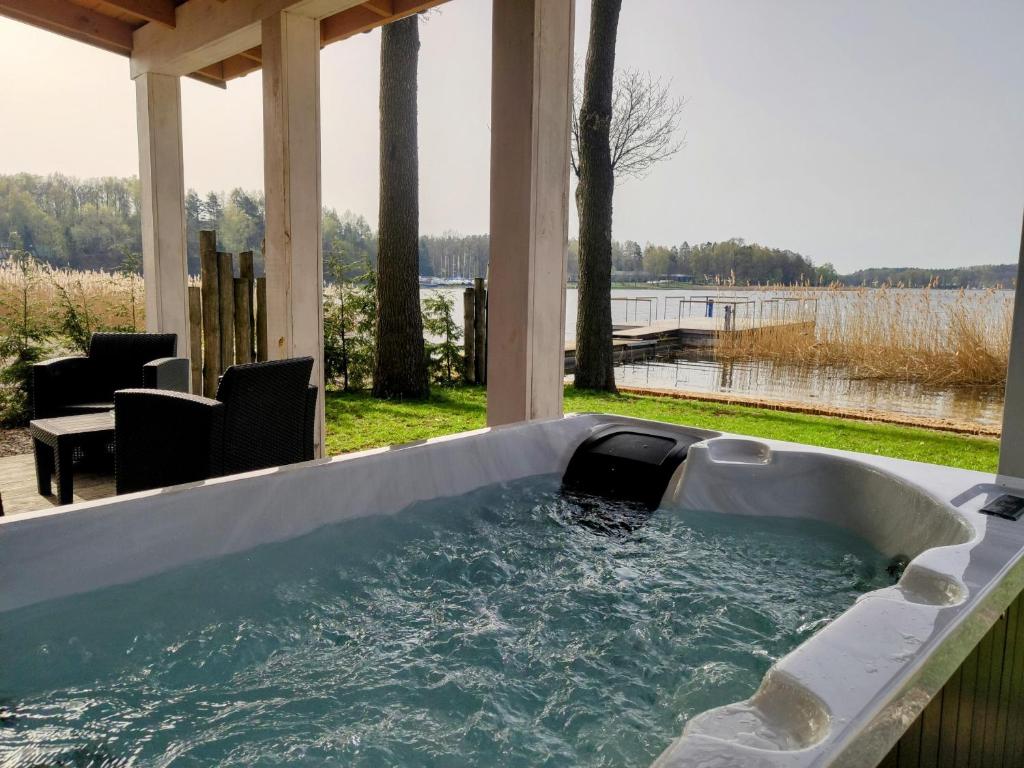 a jacuzzi tub on a porch with a view of the water at Stranda in Giżycko