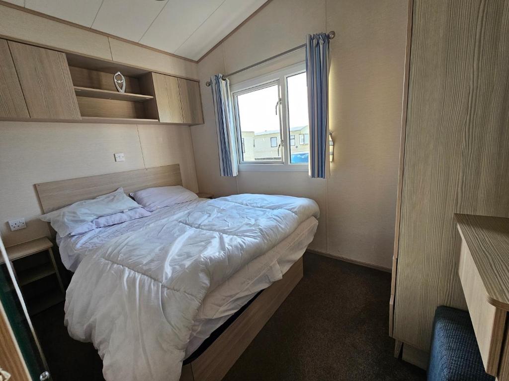 a small bedroom with a bed and a window at Caravan LEANNE in Meliden