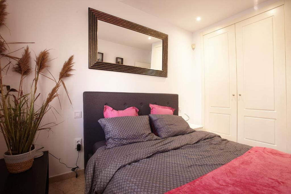 1 dormitorio con cama con almohadas rosas y espejo en Casa Allegra en Los Alcázares