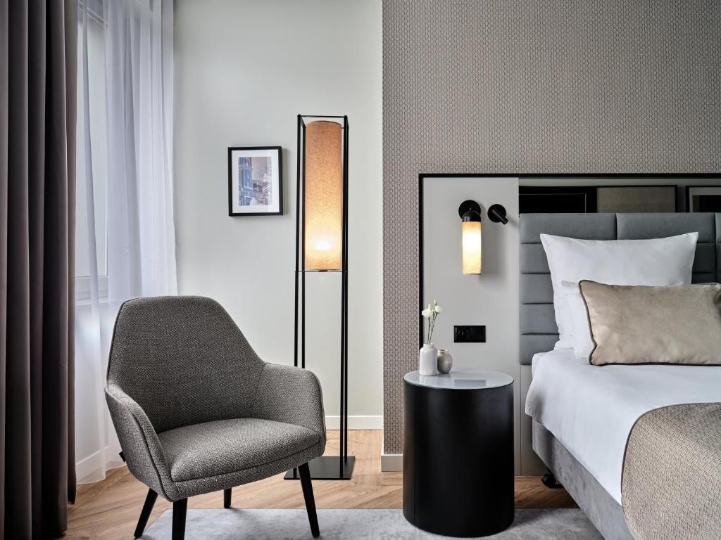 een slaapkamer met een bed, een stoel en een lamp bij Leonardo Royal Hotel Warsaw in Warschau