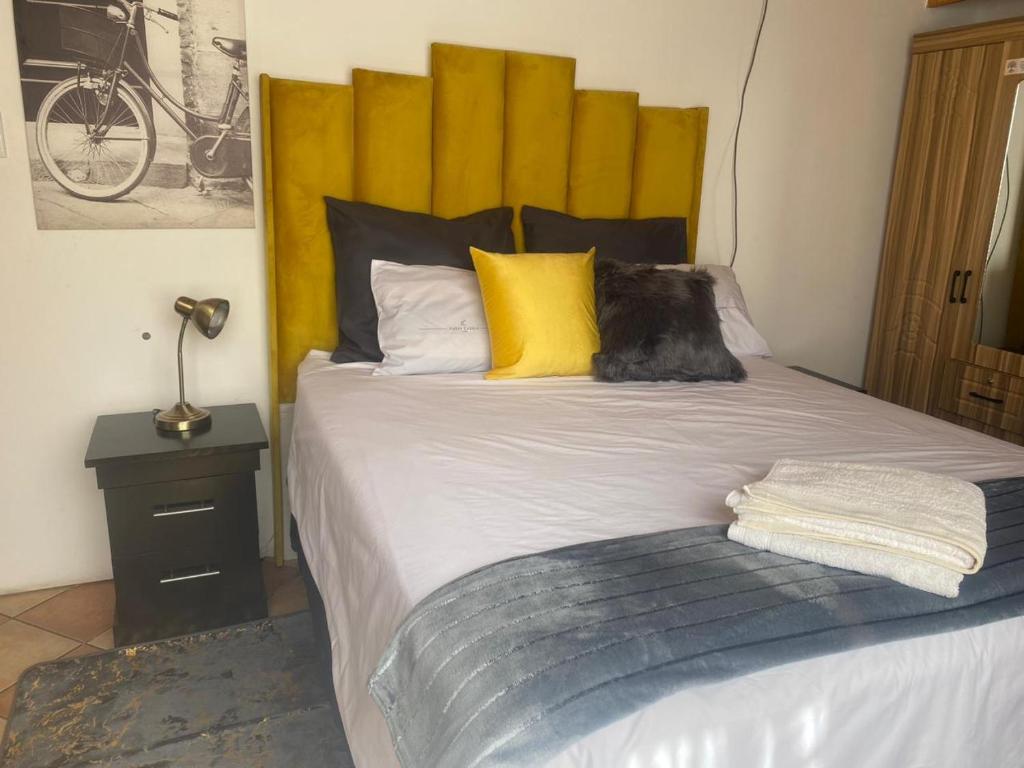 - une chambre avec un grand lit et une tête de lit jaune dans l'établissement Golden Glory Manor, à Roodepoort