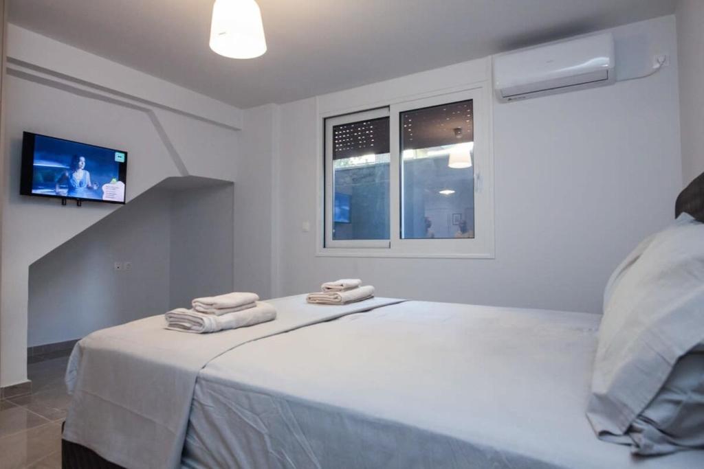 a white room with a bed with towels on it at Charming Urban Oasis 1BR Apt near Megaro Mousikis in Athens