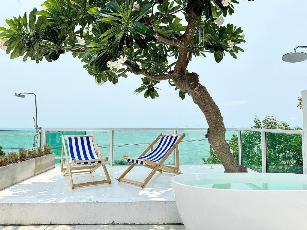 two chairs and a tree on a patio with the ocean at Gao Bayview Banchang in Rayong