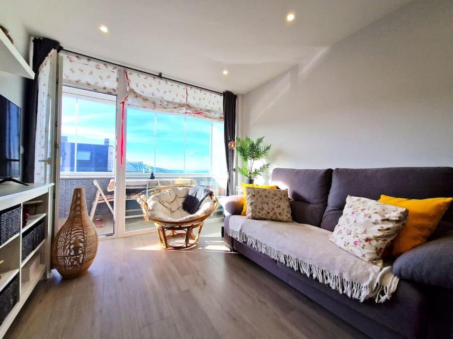 un soggiorno con divano e una grande finestra di Dúplex playa Foz. Vistas al Mar, Terraza y Piscina a Foz