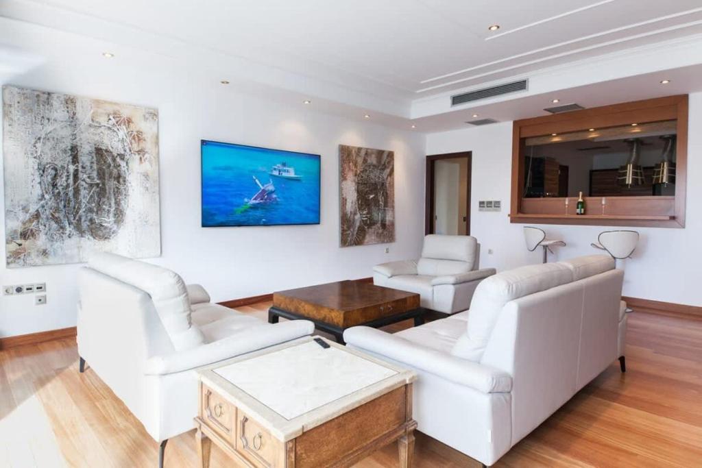 een woonkamer met witte meubels en schilderijen aan de muur bij Riviera Retreat 3 Bedroom Voula Luxury Haven Apt in Athene