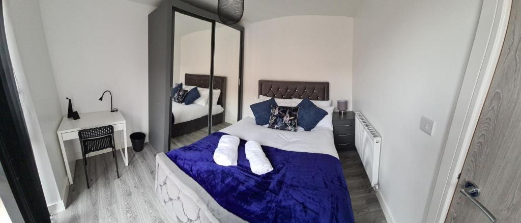 een slaapkamer met een groot bed met blauwe lakens en kussens bij SAV Apartments Loughborough - 1 Bed Flat in Loughborough