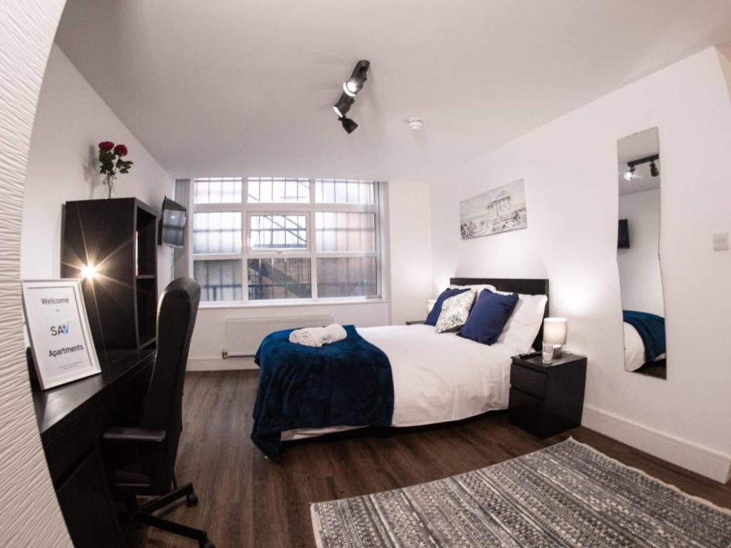 Schlafzimmer mit einem Bett, einem Schreibtisch und einem Fenster in der Unterkunft SAV Apartments Rutland Leicester in Leicester