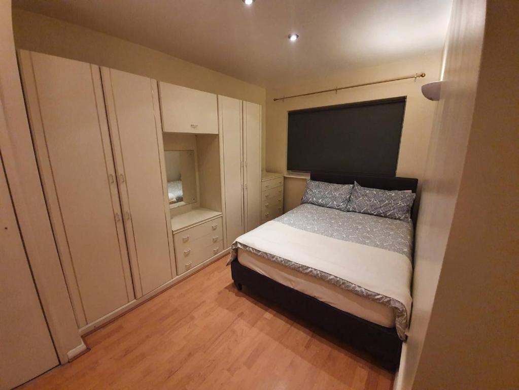 ein kleines Schlafzimmer mit einem Bett und einem Schrank in der Unterkunft SAV Apartments Watford in Watford