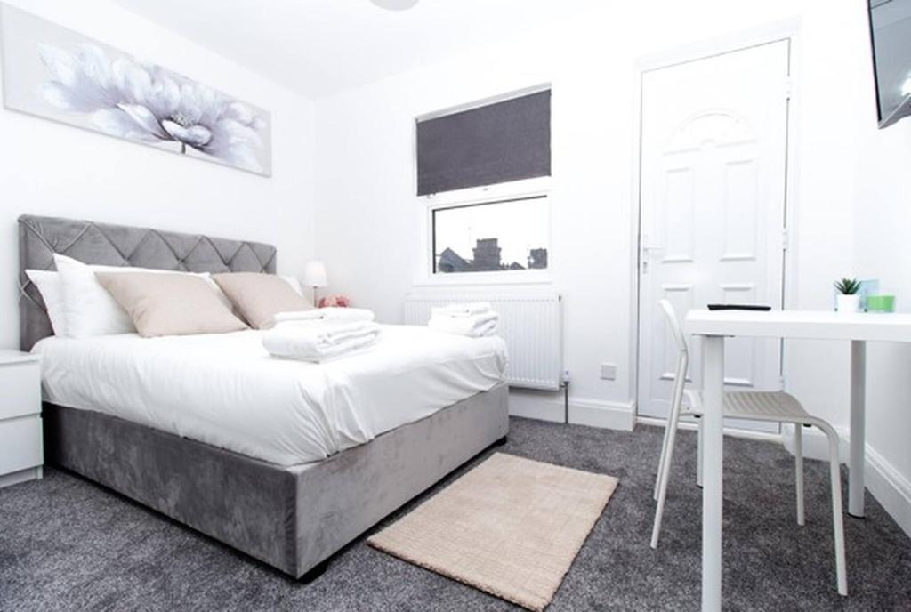 a white bedroom with a bed and a desk at SAV - 4 Bed Town House, Harrow in Harrow