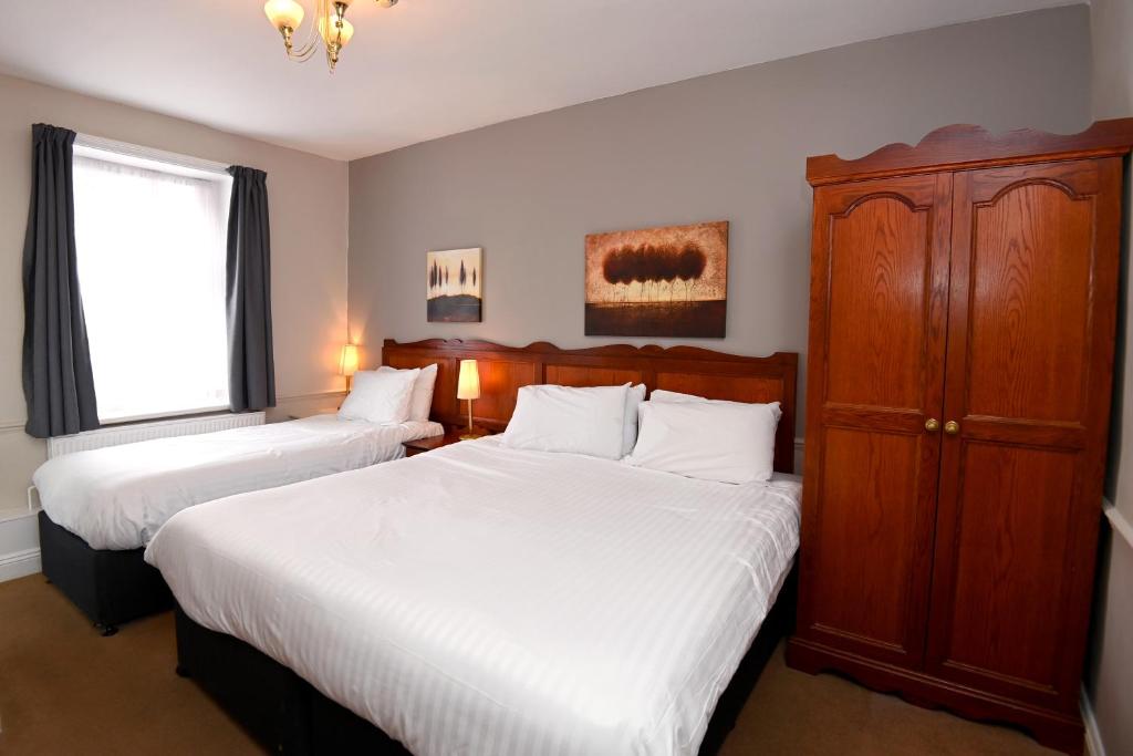 a bedroom with two beds and a cabinet and a window at Original White Hart, Ringwood by Marston's Inns in Ringwood