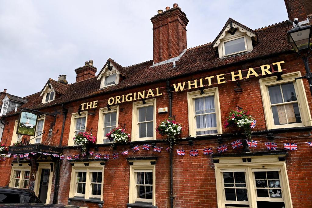Original White Hart, Ringwood by Marston's Inns في رينغوود: مبنى من الطوب الأحمر قديم ذو قبعة بيضاء أصيلة