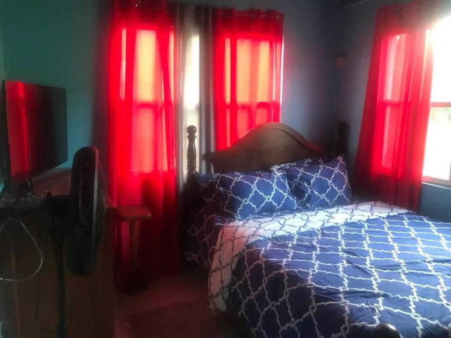 a bedroom with red curtains and a bed in a room at Cozy 2BR/1BA retreat in St.Kitts close to airport in Romneys