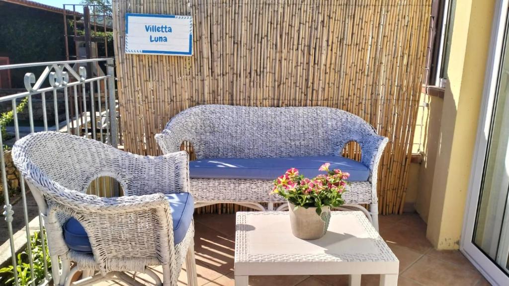 a patio with two wicker chairs and a table with flowers at Villetta Luna in San Teodoro