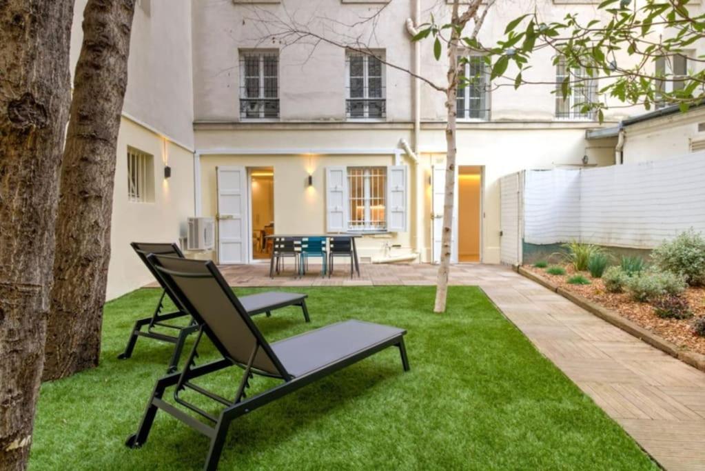 un patio avec deux chaises et une table dans une cour dans l'établissement Jardin - Jacuzzi - chambres en suite, à Paris