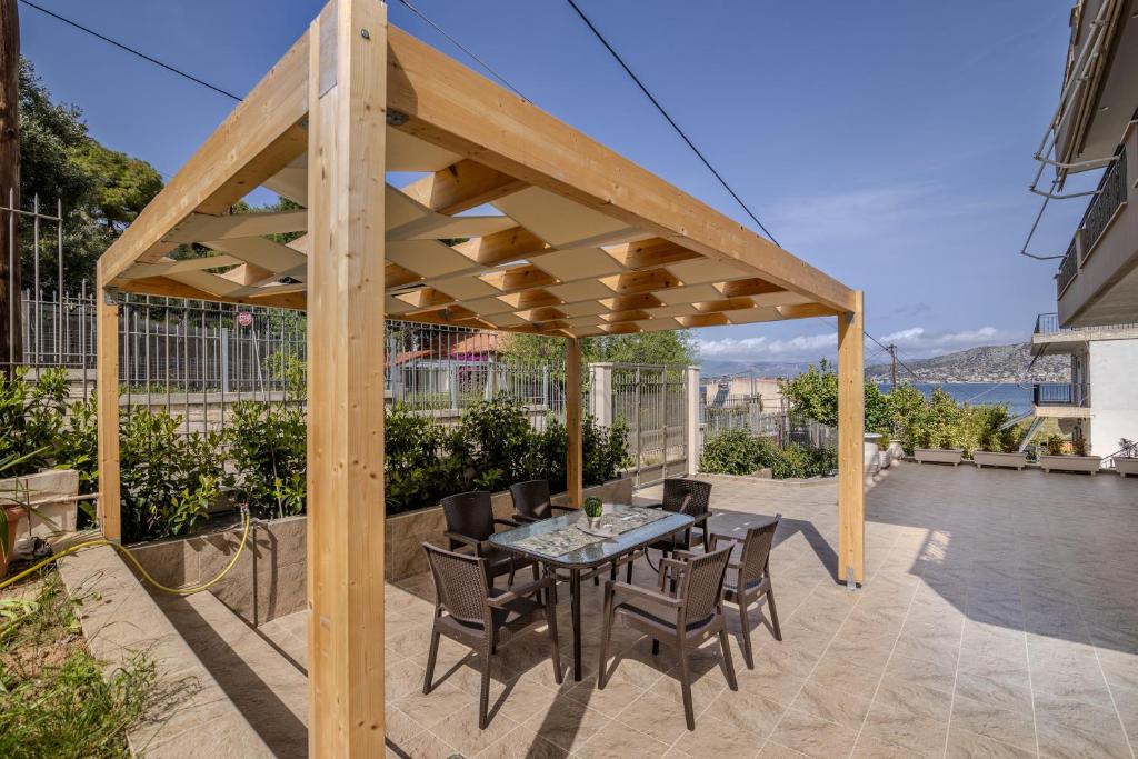 a wooden pergola on a patio with a table and chairs at George Luxury Beach House in Aiándion