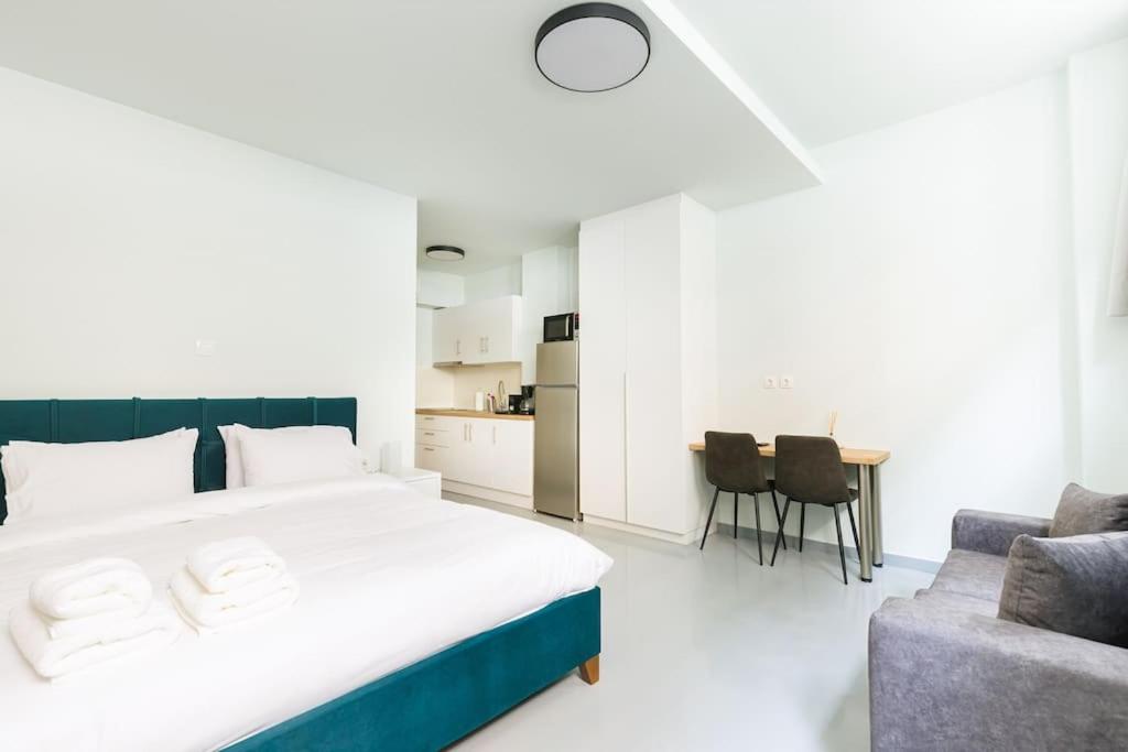 Snug studio apartment with shared garden IV في أثينا: غرفة نوم بسرير واريكة وطاولة