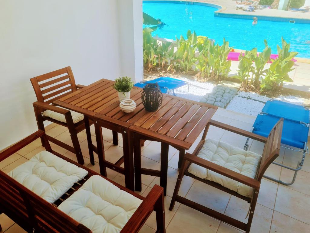 una mesa de madera y sillas con una mesa y una piscina en Blue Pearl holiday apartments with pool in kato paphos, en Pafos