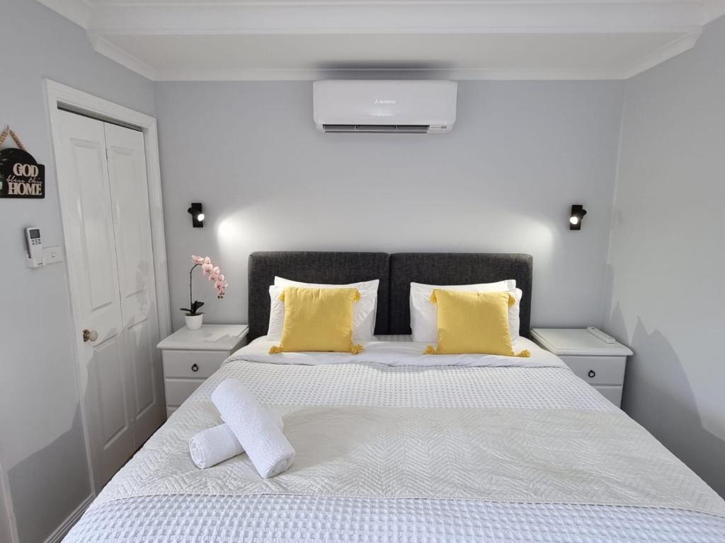 a bedroom with a large bed with yellow pillows at Guest Studio in Campbelltown 