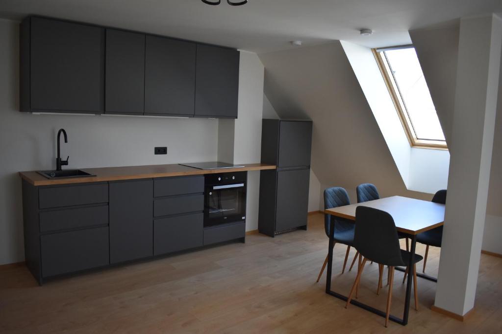 een keuken met zwarte kasten en een tafel en stoelen bij Suur-Posti Apartments in Pärnu