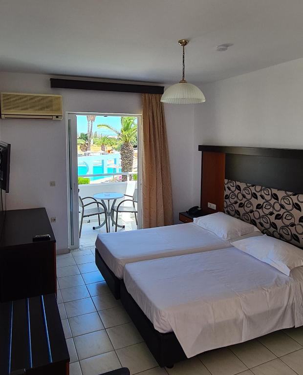 a bedroom with a bed and a view of a patio at Corali Hotel in Tigaki