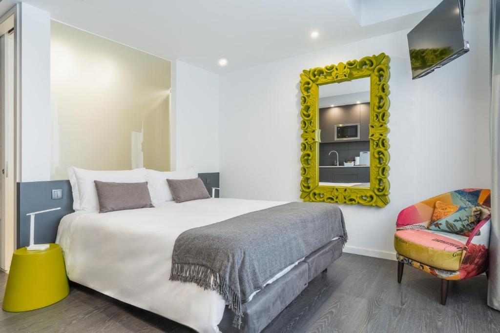 a bedroom with a bed and a mirror and a chair at Avenida Concept Studios in Aveiro