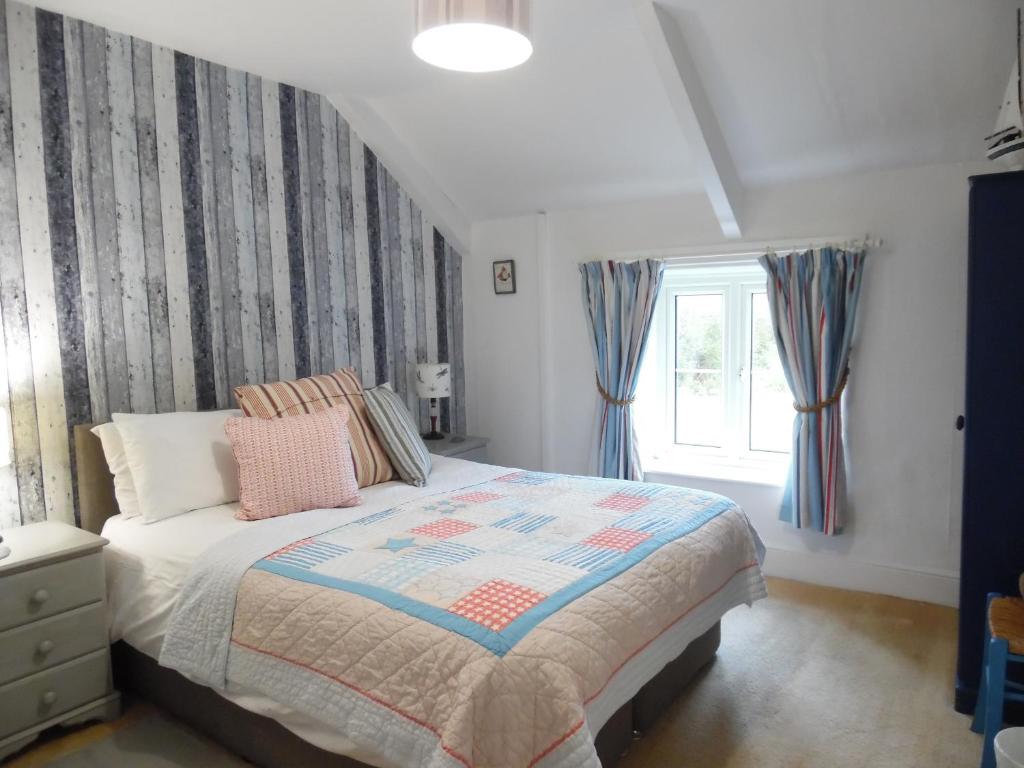 a bedroom with a bed and a window at Langdon Farm Cottage in Boyton