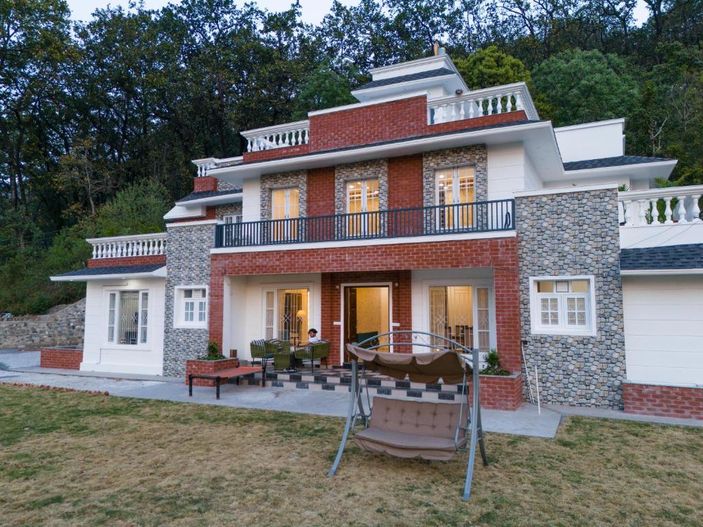 a large brick house with a balcony at The Chirpy Bungalow By LUHO Leisure in Dehradun