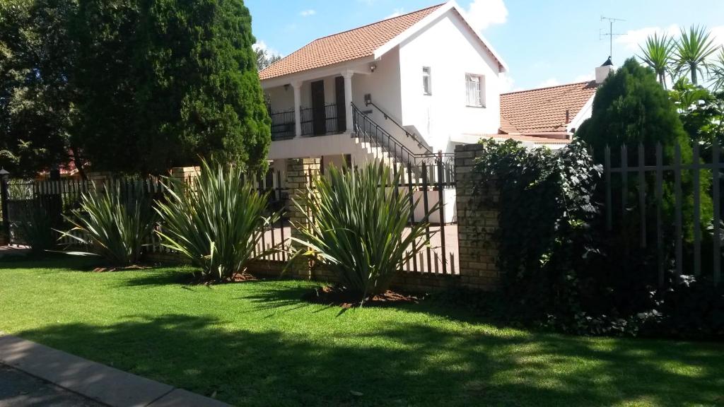 a white house with a fence and some plants at Magnolia Guesthouse & coffeeshop in Vaalpark
