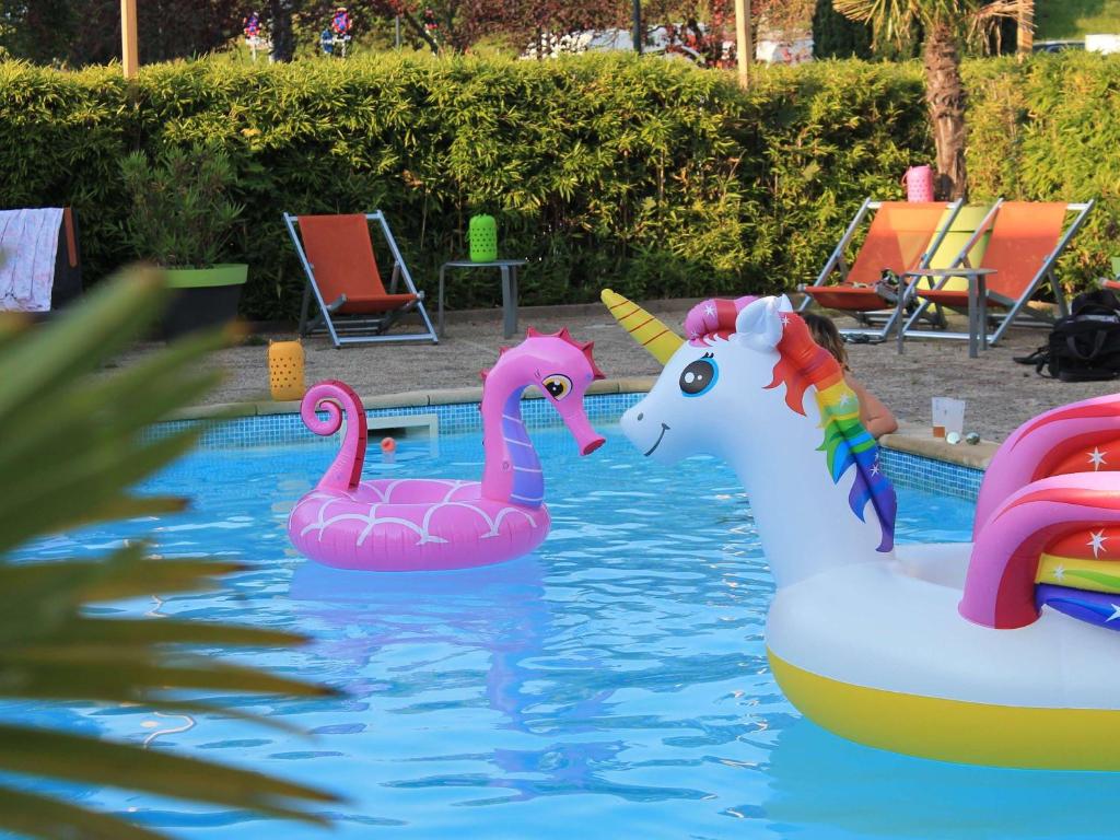 twee opblaasbare flamingo's in het water in een zwembad bij Mercure Reims Parc Des Expositions in Reims