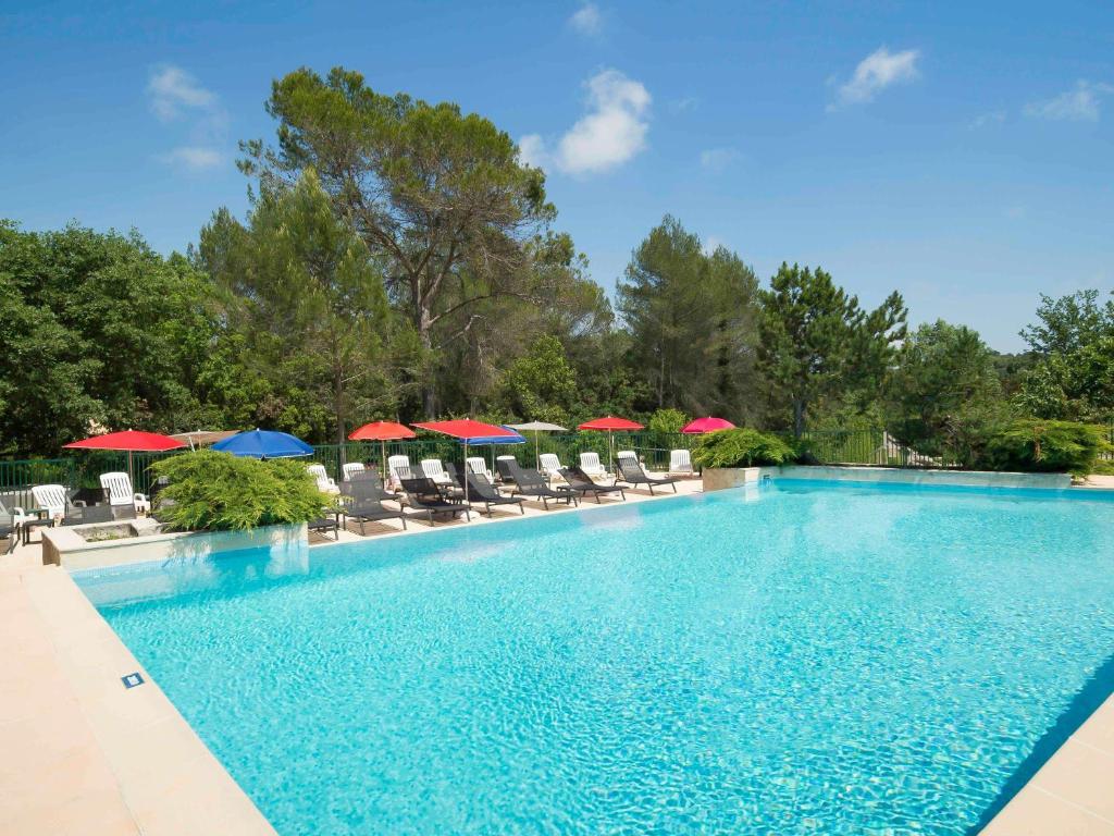 a large swimming pool with chairs and umbrellas at ibis Antibes Sophia-Antipolis in Valbonne