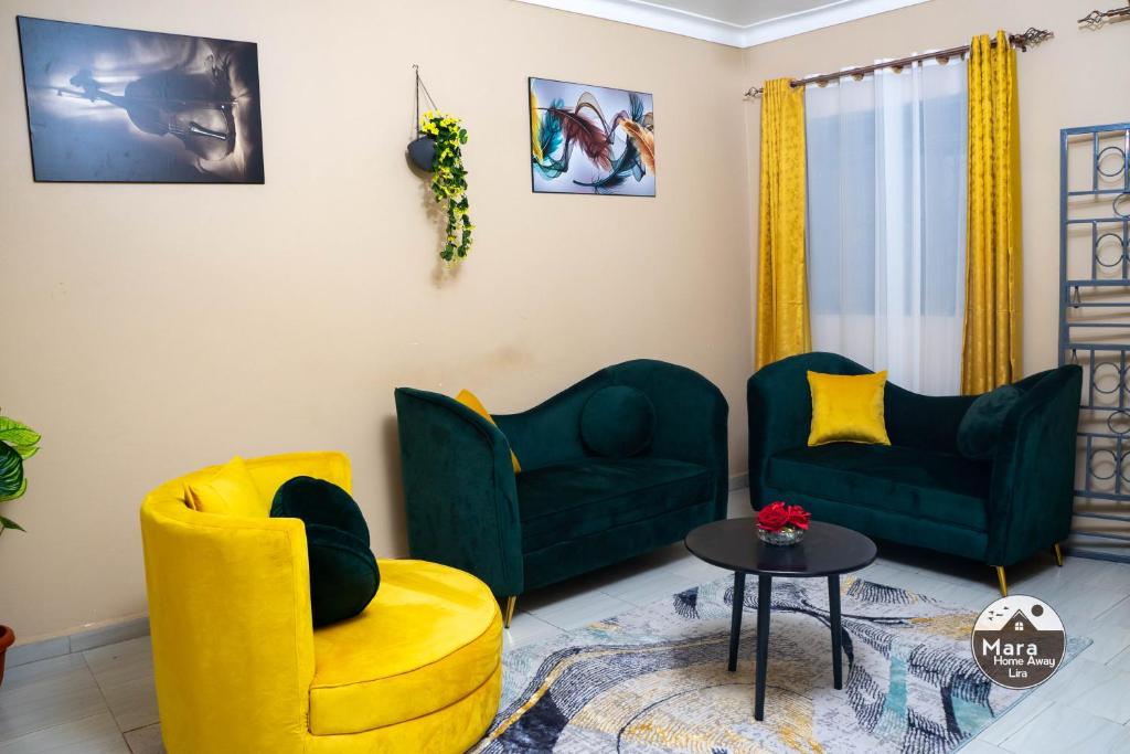 a living room with two green chairs and a table at Mara Home Away in Lira, Uganda in Lira