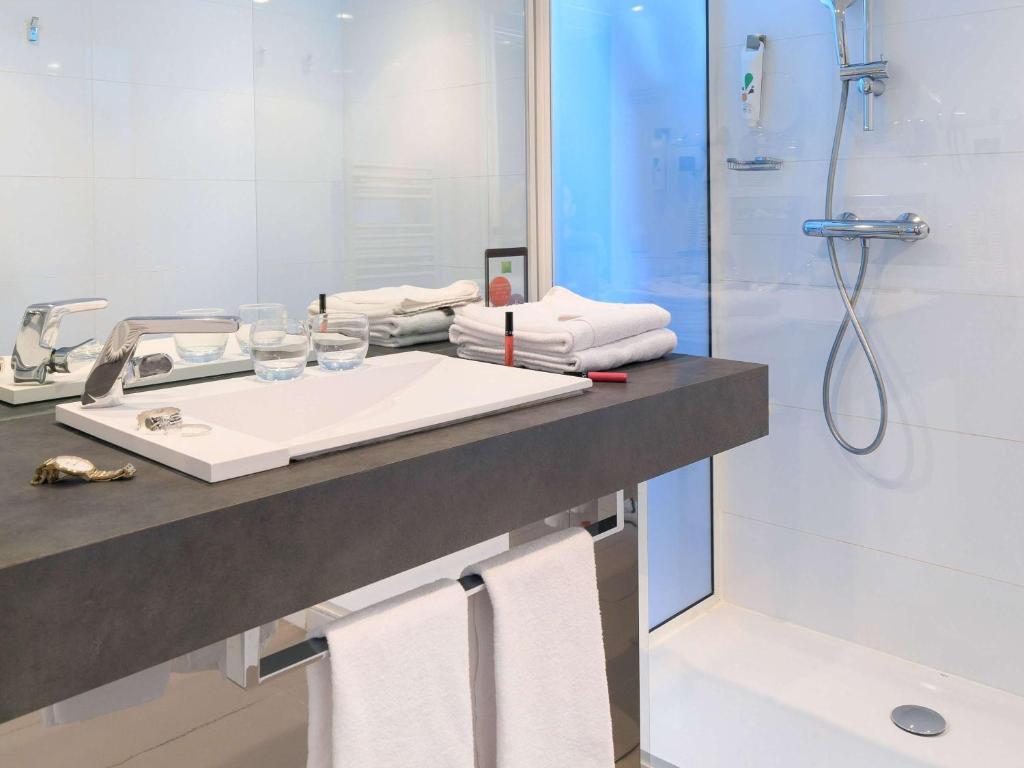 a bathroom with a sink and a shower with towels at Ibis Styles Menton Centre in Menton