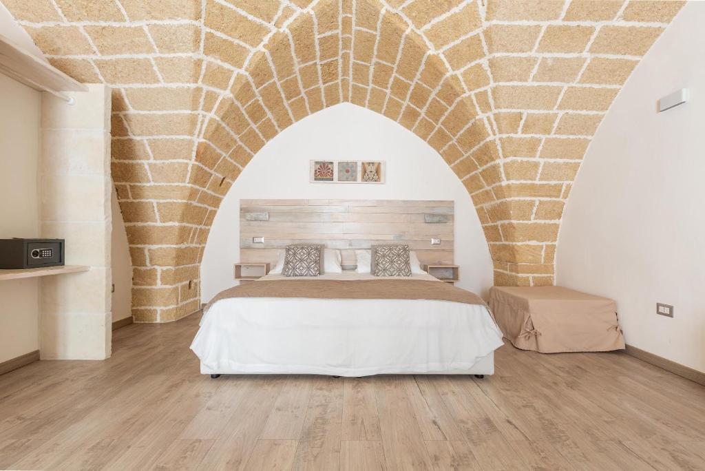 um quarto com uma cama com uma parede de tijolos em Clara Domus em Gallipoli