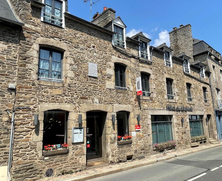 ディナンにあるHôtel du Château Dinan - Originals Boutiqueの窓に花が咲く古い石造りの建物