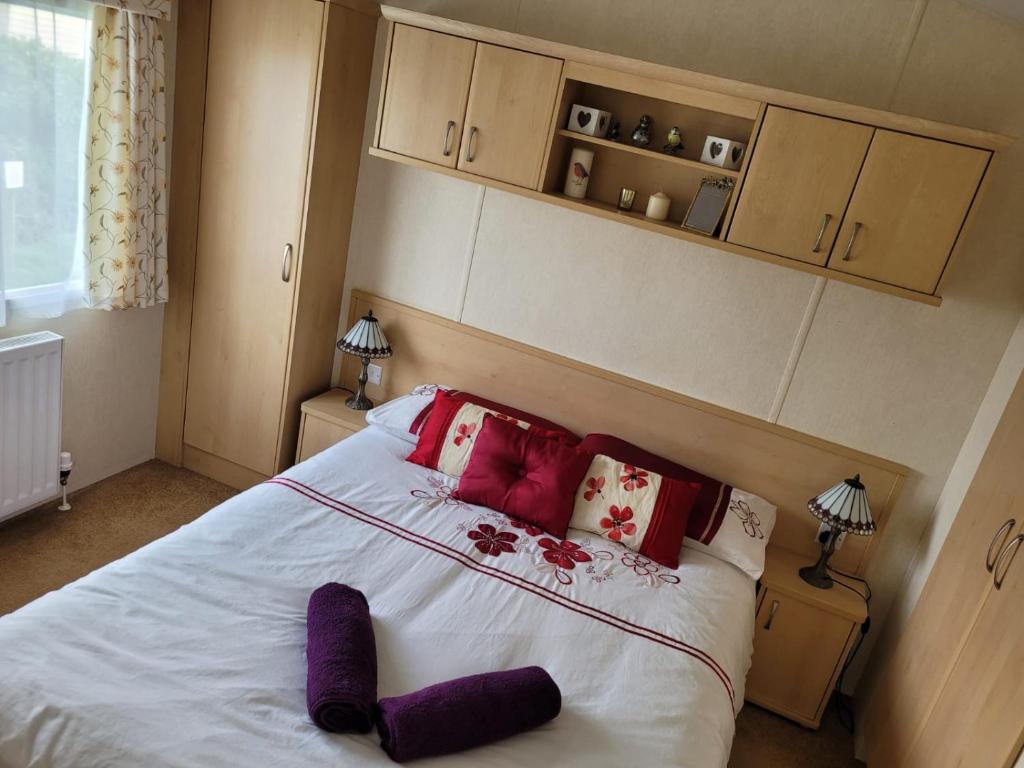 a bedroom with a large white bed with red pillows at Cosy caravan Sunbeach in Llwyngwril