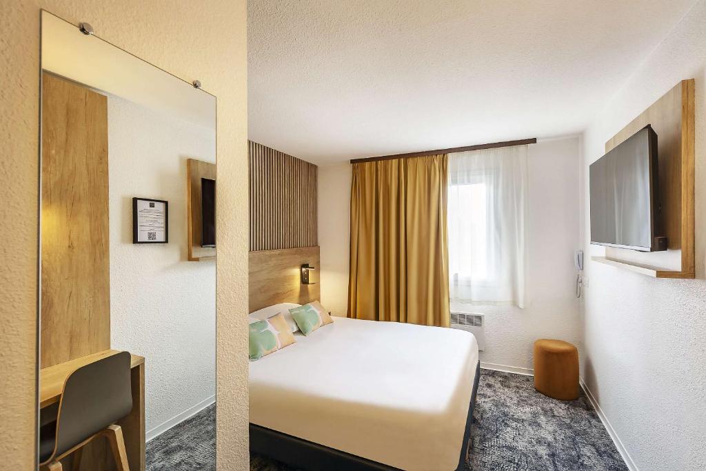 ポーにあるOstal Pau Universite - Sure Hotel Collection by Best Westernのベッドとテレビが備わるホテルルームです。