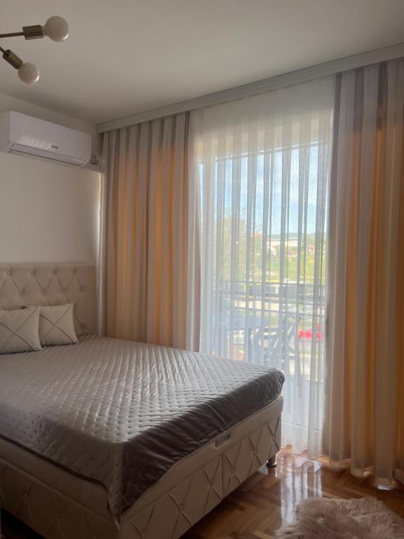 a bedroom with a bed and a large window at Apartman Nini in Kraljevo