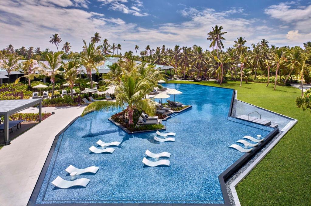 a resort with a pool with lounge chairs and palm trees at Waldorf Astoria Seychelles Platte Island in Platte Island