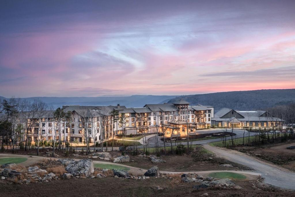 un gran edificio de apartamentos con una puesta de sol en el fondo en Cloudland at McLemore Resort Lookout Mountain, Curio Hilton, en Rising Fawn