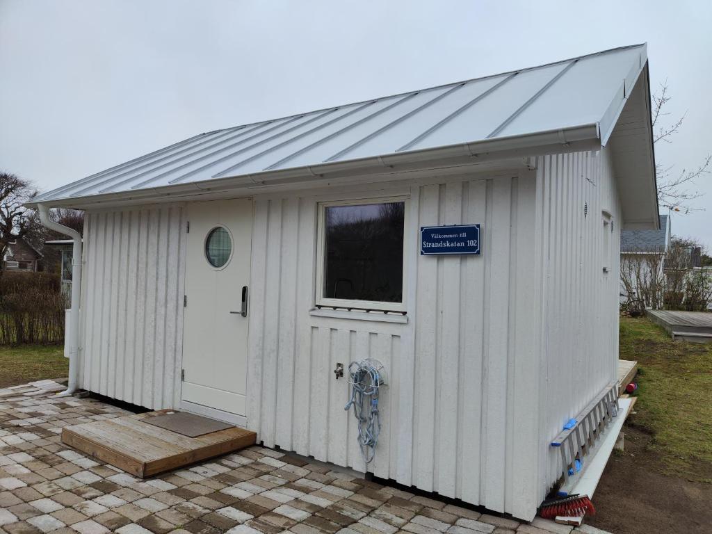 a white shed with a door and a window at Strandskatan 102 in Halmstad