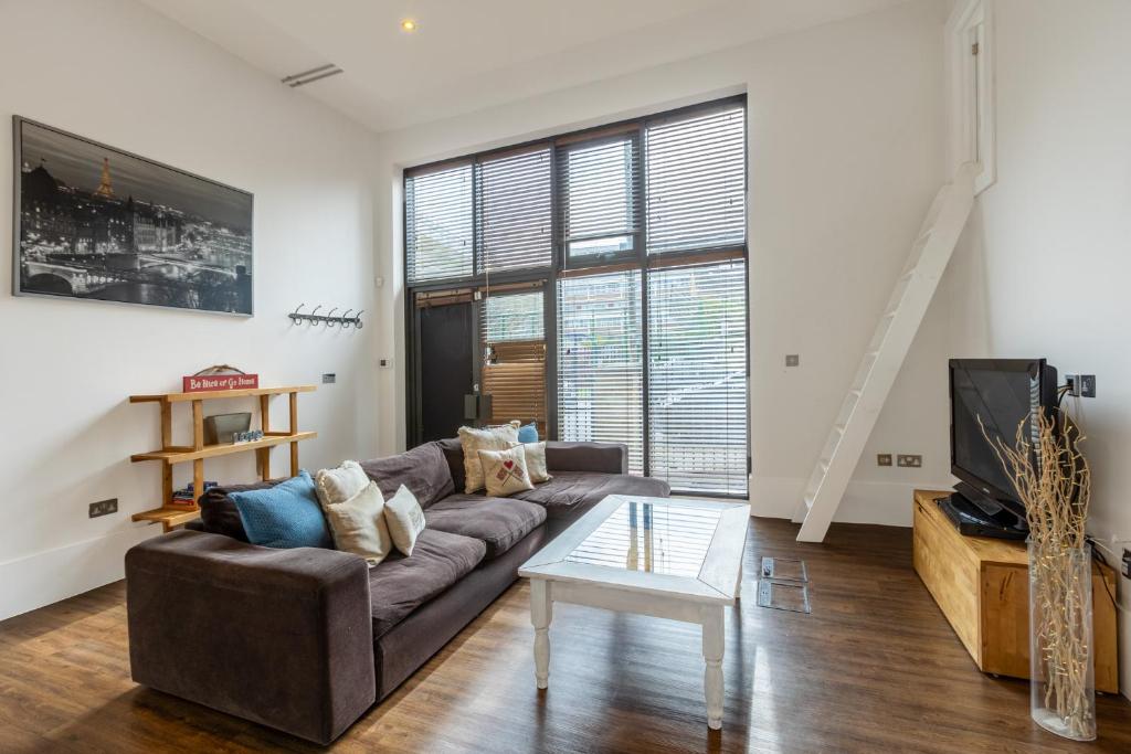 uma sala de estar com um sofá e uma televisão em Gorgeous loft style 3BR apt, Battersea em Londres