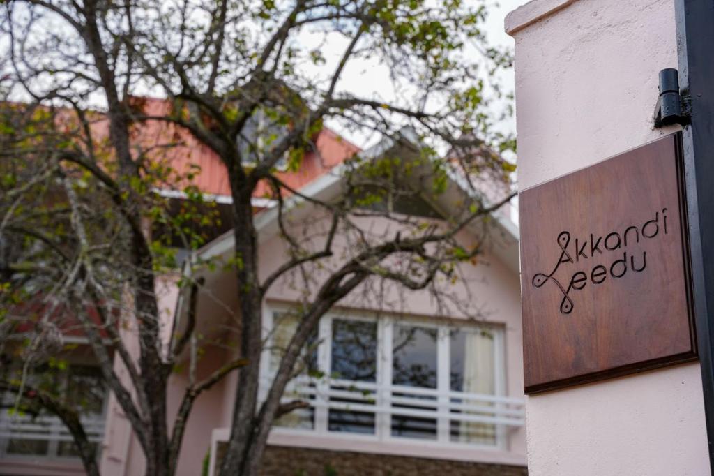 a sign on the side of a house with a tree at AKKANDI VEEDU FAIRY FALLS BY XACRO STAYS in Kodaikānāl