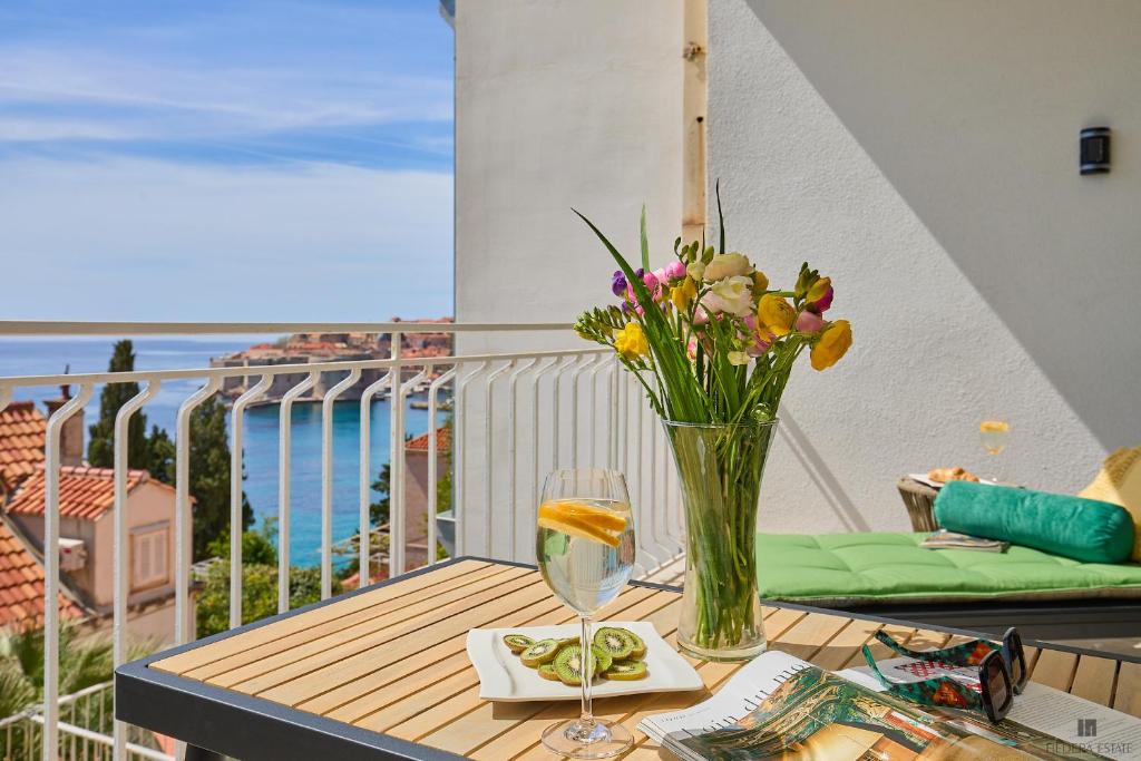 una mesa con un jarrón de flores y una copa de vino en Hedera A9, en Dubrovnik